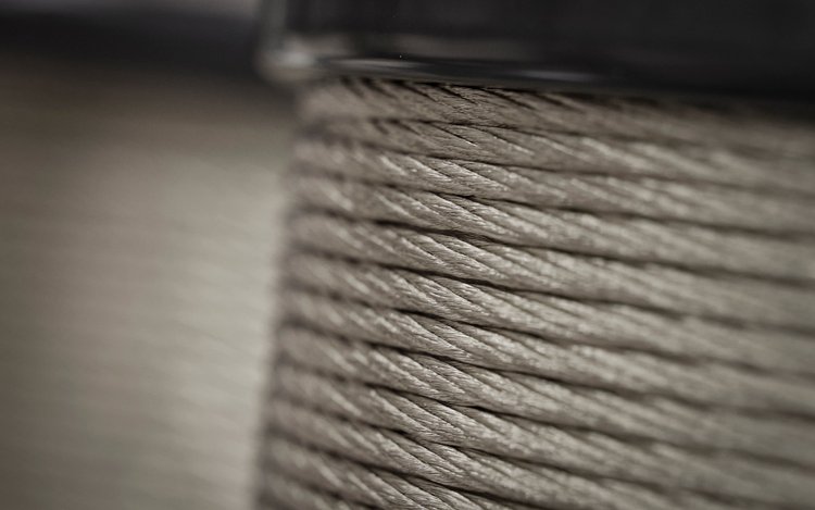 Makroaufnahme einer aufgewickelten Aluminiumlitze auf einer Spule mit deutlich sichtbarer Verseilstruktur.